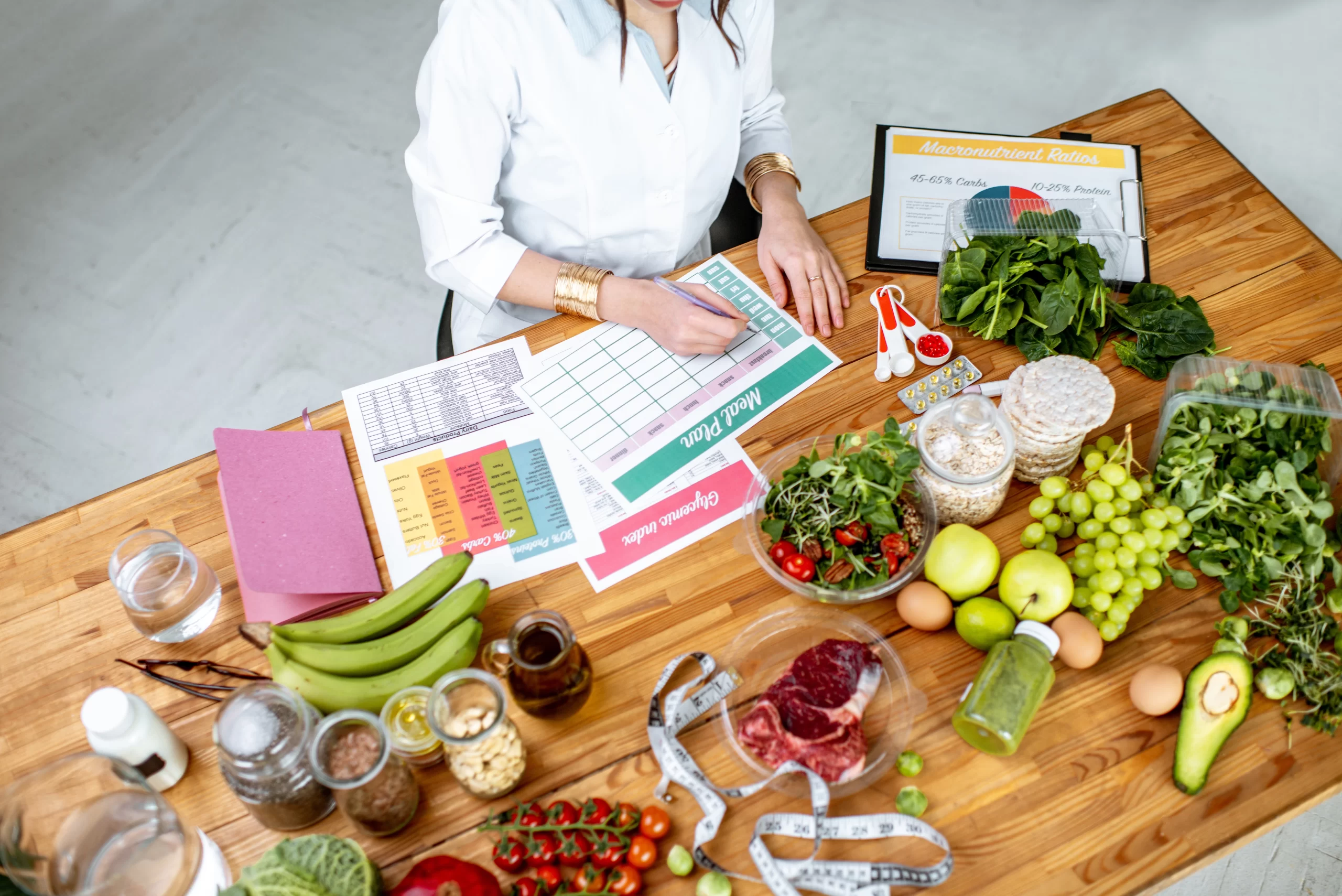 Blog 21 Nutritionist writing a balanced meal plan surrounded by fresh vegetables, fruit, and lean protein for workout energy